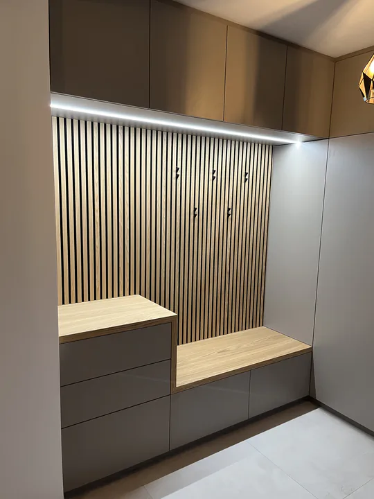 Garderobe mit beleuchteter Akustik-Lamellenwand, Eichenbank und Ladenblock