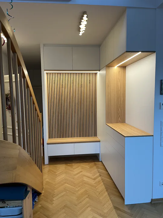 Flurgarderobe neben der Treppe, mit Lamellenwand und Eichenbank über Fischgrätparkett