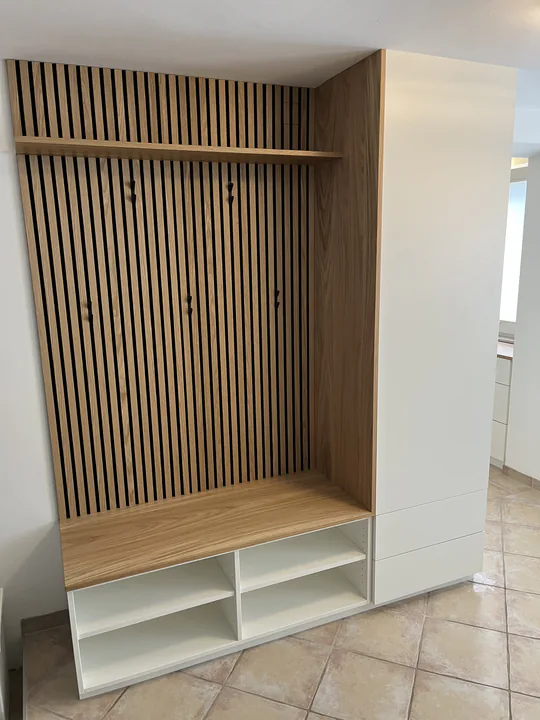 Garderobe mit Lamellenwand aus Eiche, Hutablage und Sitzbank über offenen weißen Schuhfächern