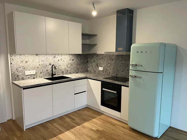 Weiße L-Küche mit Steinrückwand, Dunstabzug und mintgrünem Retro-Kühlschrank