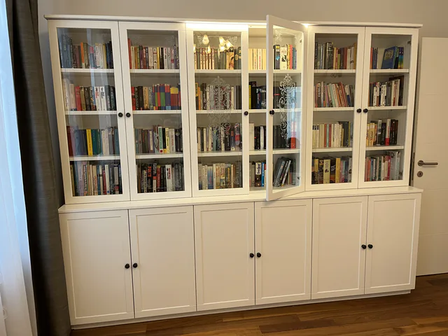 Raumhohe weiße Bücherwand, eine der Glastüren steht offen