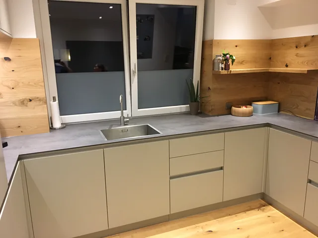 Neue Arbeitsplatte in Betonoptik mit neuen Fronten darunter, dahinter eine Rückwand aus Asteiche mit Wandablage