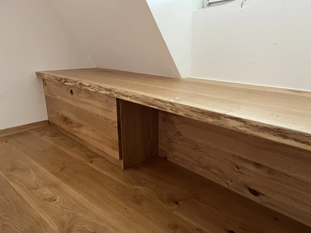 Durchgehende Baumkantenplatte, die unter der Dachschräge als Arbeitsfläche weitergeführt ist