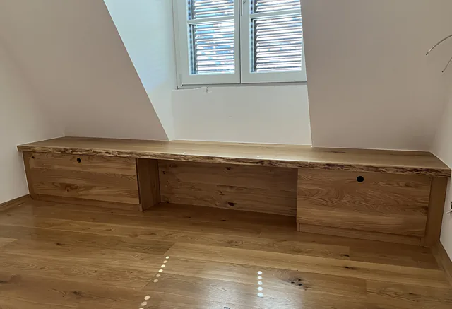 Langes Sideboard aus Eiche unter einer Dachschräge, darauf eine durchgehende Platte mit Baumkante