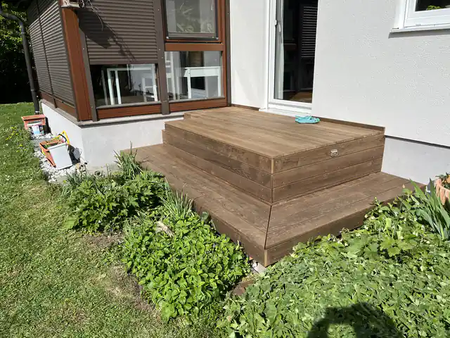 Terrassenpodest aus Holz mit zwei Stufen vor einer Terrassentür