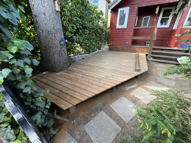 Terrassendeck, dessen Dielen genau um einen gewachsenen Baumstamm ausgeschnitten sind