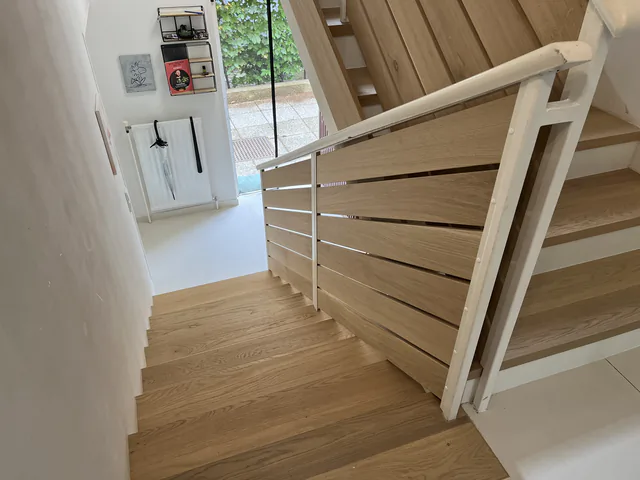 Blick von oben über eine Eichentreppe in den offenen Wohnraum