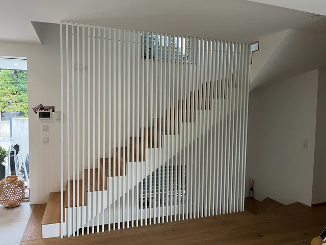 Treppenaufgang hinter einer raumhohen weißen Lamellenwand