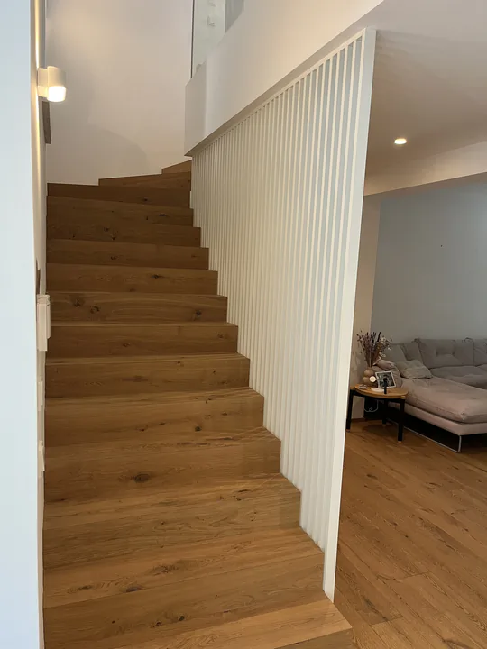 Treppe mit weißer Lamellenverkleidung anstelle eines offenen Geländers