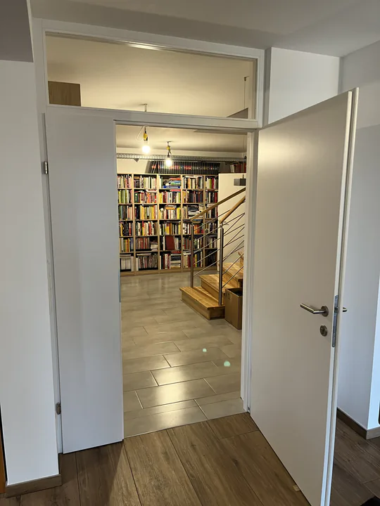Geöffnete weiße Zimmertür mit Blick in einen Raum voller Bücherregale